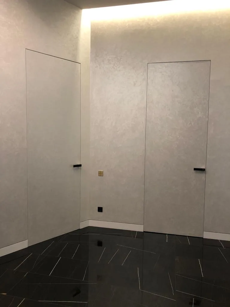ușă invizibilă integrată în perete cu finisaj decorativ alb gri